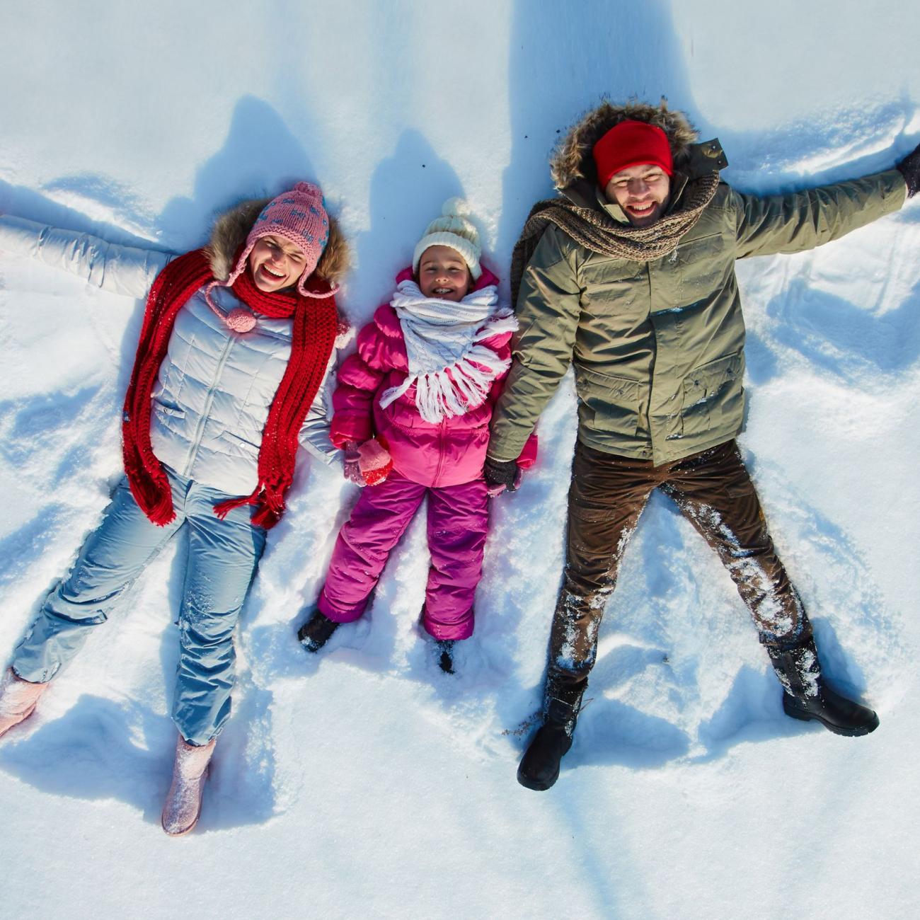Familie liegt im schnee und freut sich