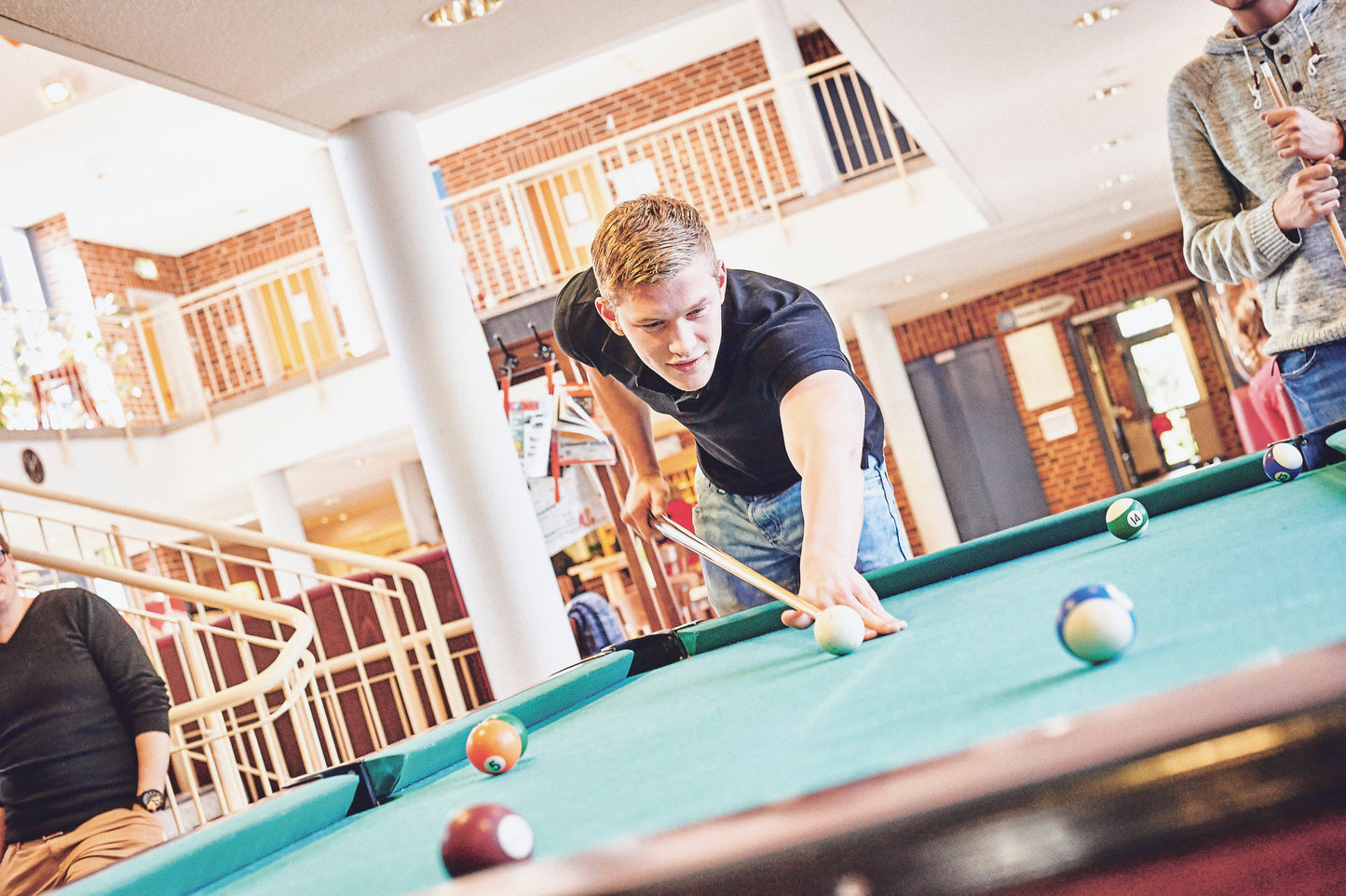 Foto eines Billiardtisches mit 3 Spielern in der Jugendherberge