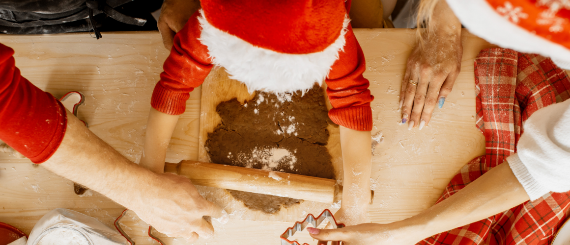 Familie mit roten Nikolausützen backen zusammen Plätzchen