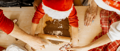 Familie mit roten Nikolausützen backen zusammen Plätzchen
