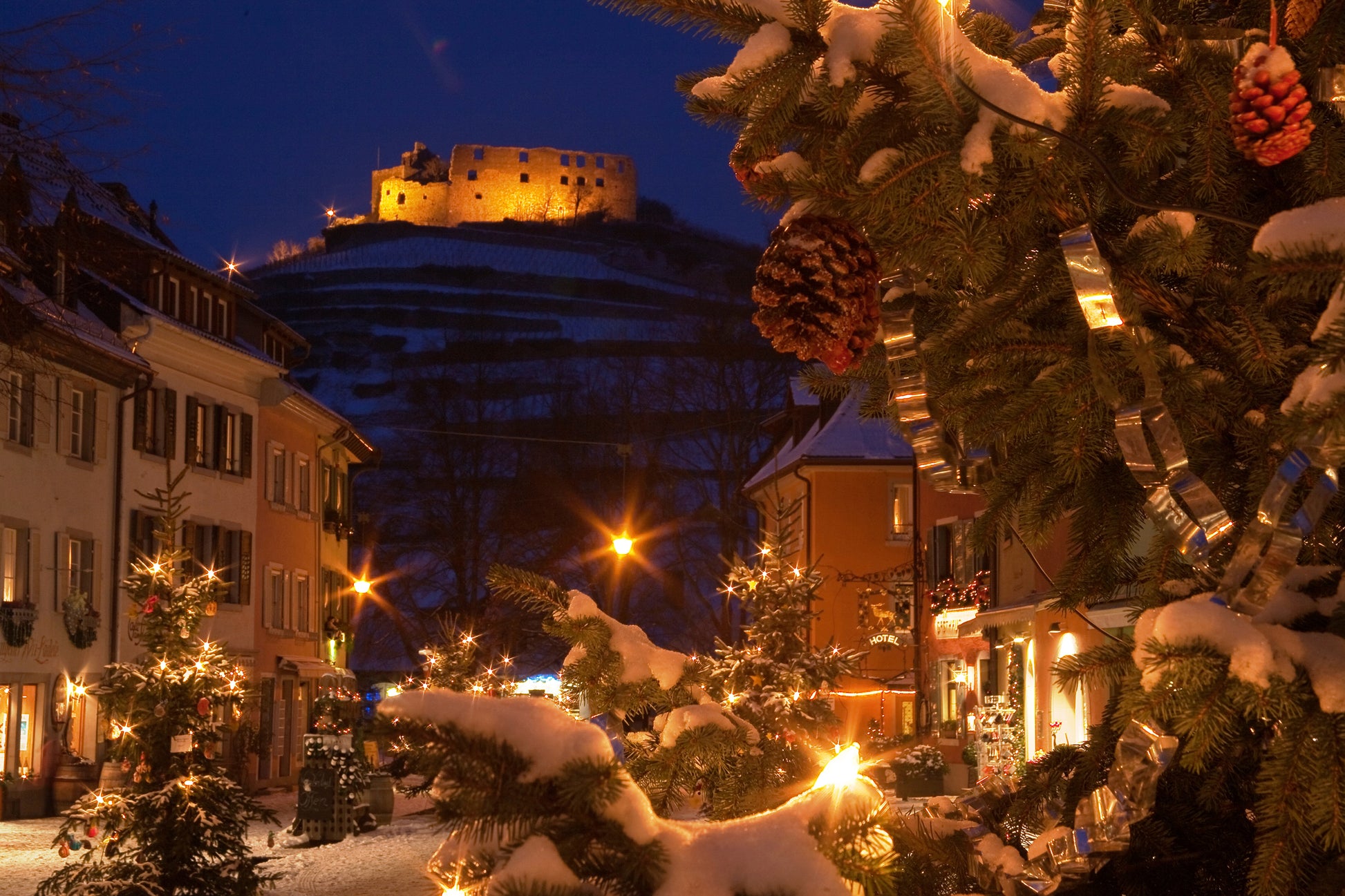 Winterliche Ansicht von Staufen mit geschmückten weihnachtsbäumen und einer beleuchteten Burg